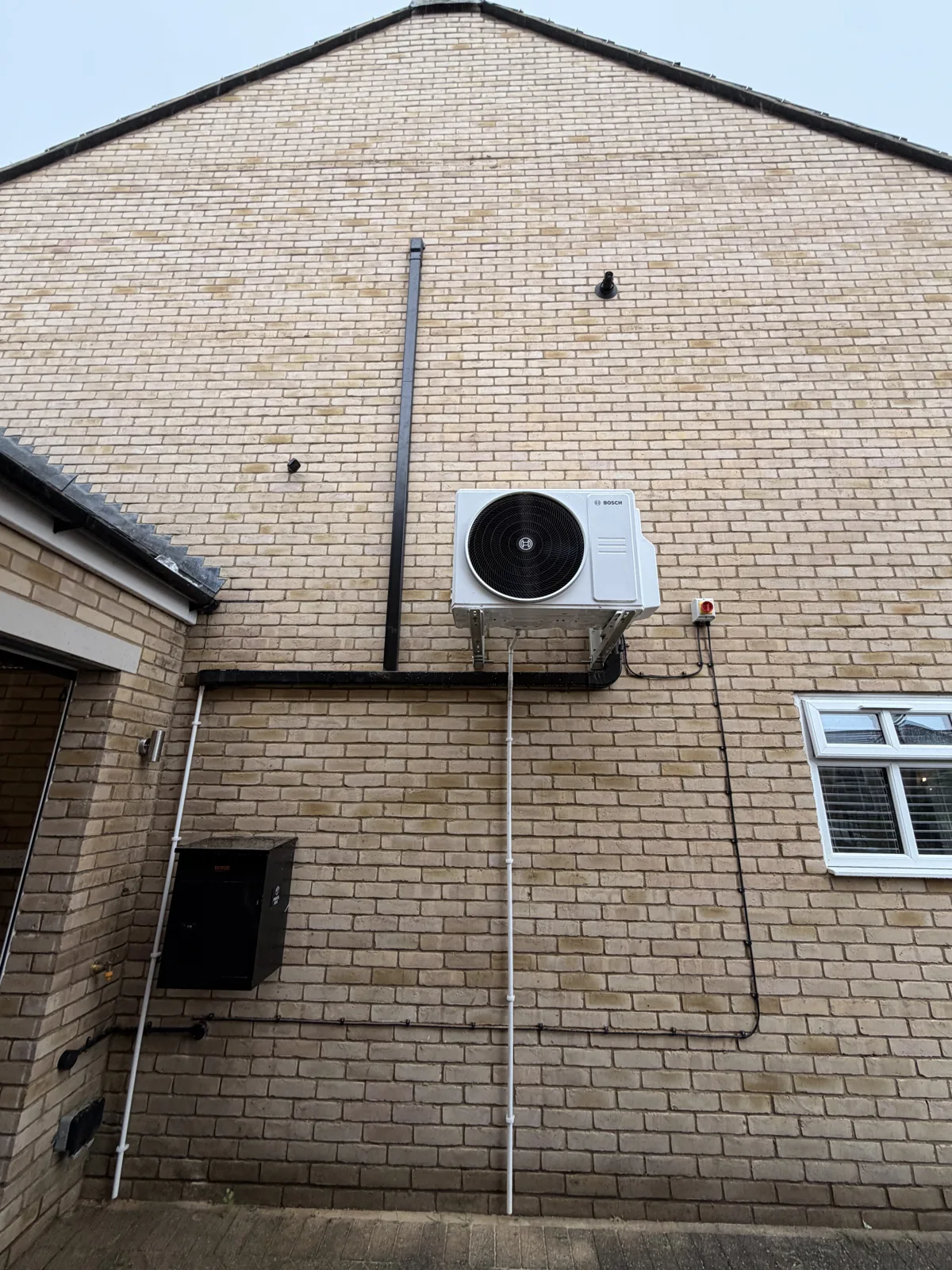 Bosch multi split external unit on a brick wall, with the pipework and cable neatly trunked