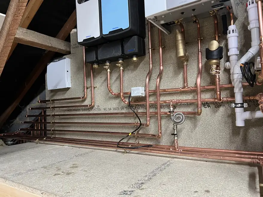Copper manifold, valves and heating controls in a loft plant area